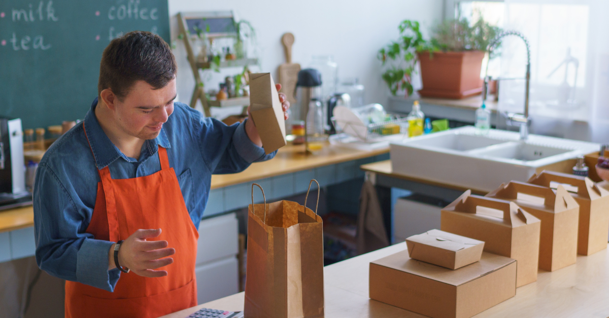 Photo of person with disabilities indoors behind counter and preparing take-away food orders