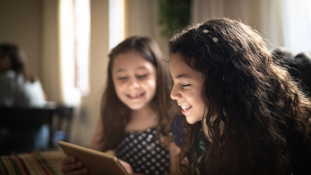 A picture with kids smiling and playing with a digital tablet