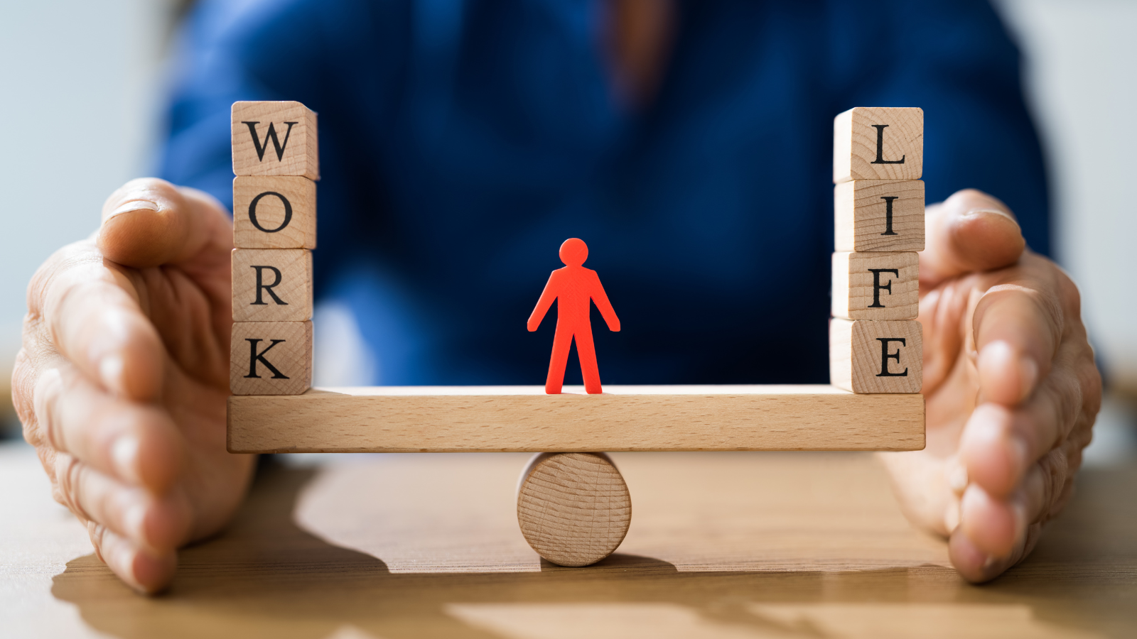 A wooden balance weighing "work" and "life" with a drawn character in the middle of the balance.